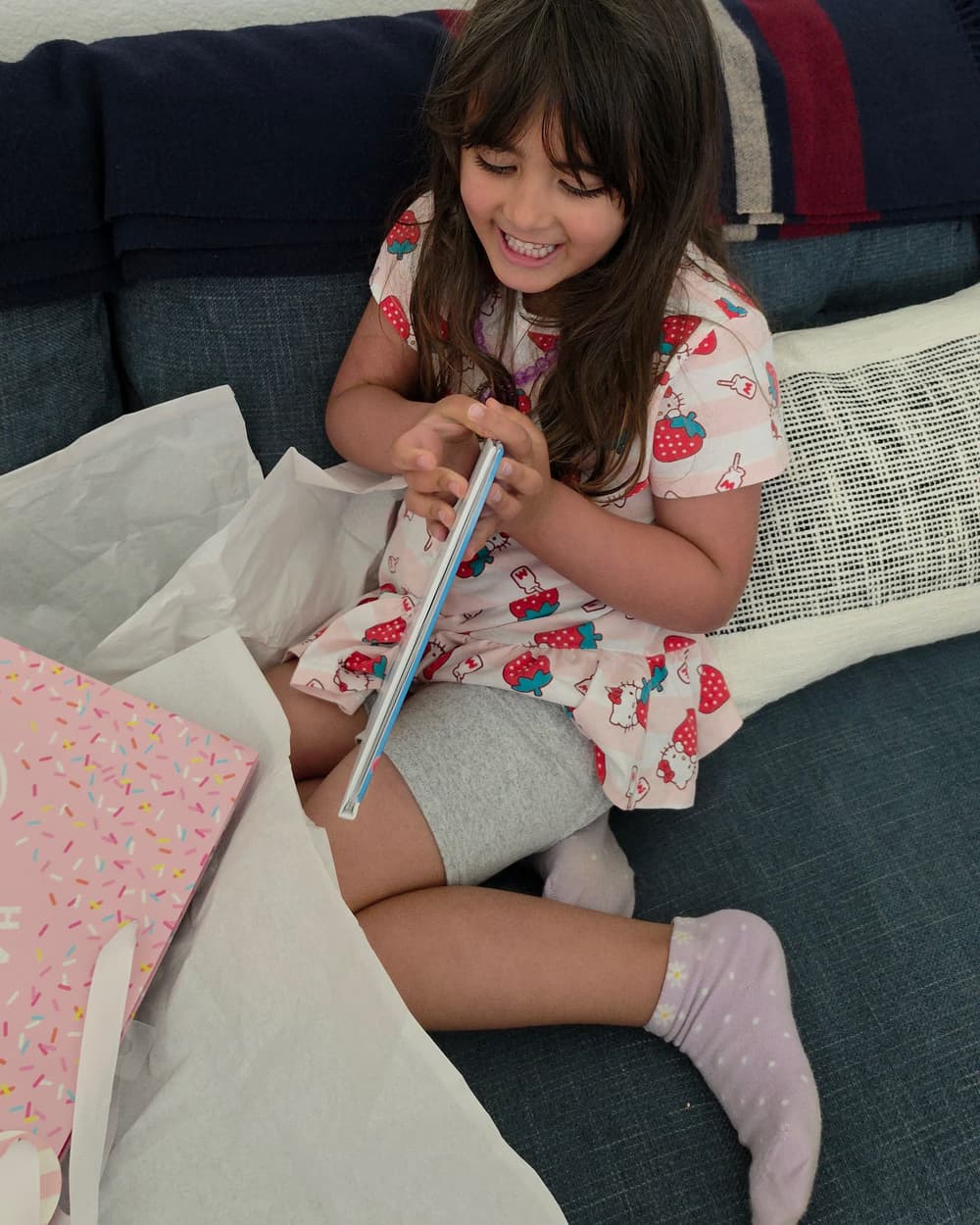 Kiera sitting on the couch at home, smiling as she opens her personalized Story Genie hardcover